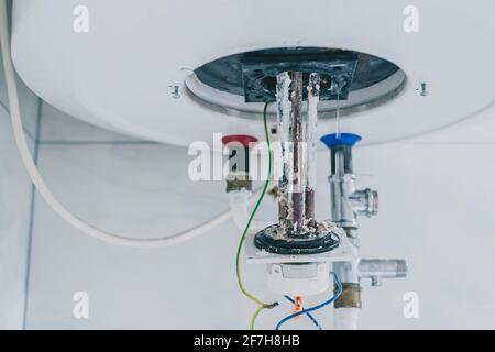 Estrazione di un riscaldatore elettrico dalla caldaia o dal riscaldatore dell'acqua per rimuovere i residui di calcare su di esso come parte di una manutenzione. Termostato elettrico in fase di rimozione Foto Stock