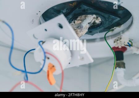 Estrazione di un riscaldatore elettrico dalla caldaia o dal riscaldatore dell'acqua per rimuovere i residui di calcare su di esso come parte di una manutenzione. Termostato elettrico in fase di rimozione Foto Stock