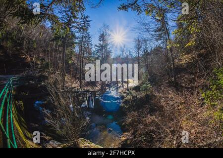 Ruota d'acqua surgelata in lontananza in una stretta valle in una giornata di sole in natura. Foto Stock