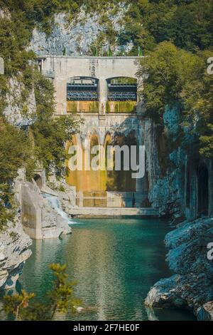 Piccola diga d'acqua di Podselo nel fiume Soca vicino alla maggior parte na Soi, diga d'acqua circondata da verde lussureggiante e bianco roccia gesso in una giornata estiva. Foto Stock
