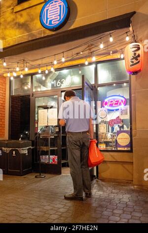 L'autista del Doordash che tiene in mano una borsa termica con il marchio Doordash e che tiene un cellulare attende di ritirare un ordine fuori dal ristorante Ramen Hiroshi nel centro di Walnut Creek, California, di notte, 5 marzo 2021. (Foto di Smith Collection/Gado/Sipa USA) Foto Stock