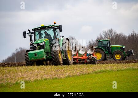 Trattore con un aratro che prepara il suolo di un campo per piantare, agricoltura, molla, Foto Stock
