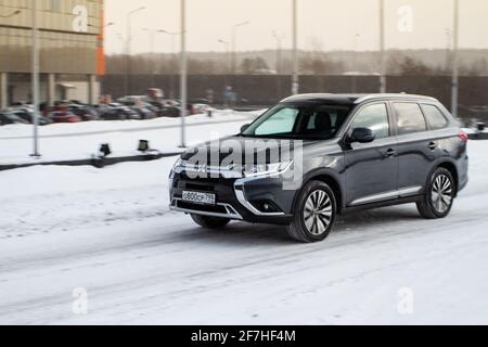 MOSCA, RUSSIA - 30 GENNAIO 2021 Mitsubishi Outlander in movimento vista laterale anteriore. Terza generazione di SUV crossover compatto giapponese prodotto da Mitsu Foto Stock