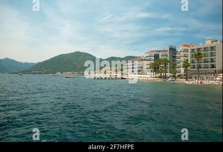 Spiaggia con edifici per gli hotel vicino alla baia con bianco barche e barche con palme verdi sullo sfondo di un cielo nuvoloso Foto Stock