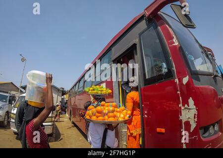 Immagine fisheye delle donne africane dalla gambia che vendono frutta e. Altre merci sul terminal dei traghetti di Banjul al passeggeri sull'autobus che viaggiano tra Foto Stock