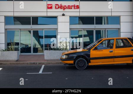 DAKAR, SENEGAL, 22 2018 FEBBRAIO: Un vecchio taxi nero e giallo attende i passeggeri di fronte a un cancello di partenza su un nuovo aeroporto. Porte visibili Foto Stock