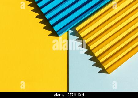 Trama della carta astratta di colore blu e giallo. Carta piegata con ombre solari dure, forme geometriche e linee. Sfondo minimalista. Disposizione piatta. Copia Foto Stock
