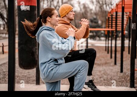 Giovane coppia in outfit sportivo facendo allenamento mattutino all'aperto. Giovane uomo e donna che si stretching muscoli prima di correre su strada sport terra Foto Stock