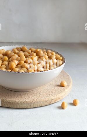 Ceci bolliti in una ciotola beige in cucina. Concetto di cucina vegetariana. Orientamento verticale. Spazio di copia. Foto Stock