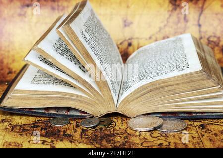 Vecchie monete d'argento del 1902 e un libro antico da 1763 su una mappa del mondo Foto Stock