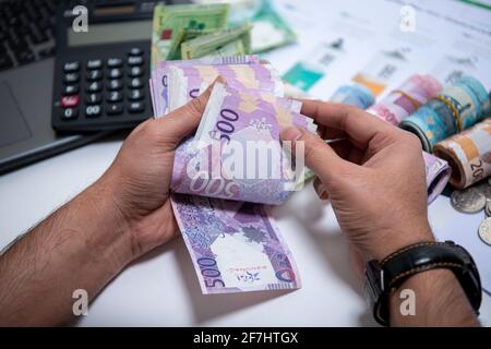 Mani degli uomini che tengono e contando le banconote della Banca Qatari. 500 nuove note di Rial. Concetto di business e finanza Foto Stock