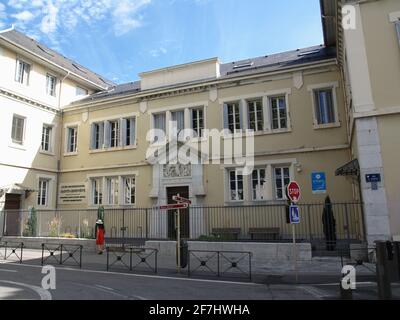 Donna in abito rosso a piedi oltre la scuola professionale privata Sainte Geneviève a Chambery, Francia Foto Stock