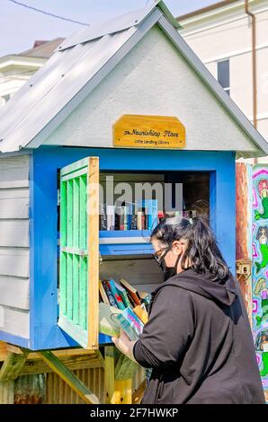 Una donna seleziona i libri presso la Little Free Library at Ruth’s Roots, 3 aprile 2021, a Bay Saint Louis, Mississippi. Foto Stock