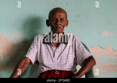 Un ritratto di vecchio nonno indonesiano seduto in sedia Foto Stock