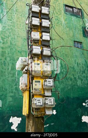 Molti vecchi contatori elettrici sporchi attaccati ad un palo lungo la strada, che collega l'elettricità alla casa residenziale sull'isola di Boracay, Filippine, Asia Foto Stock