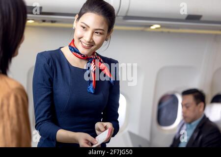 L'equipaggio di cabina o la Stewardess salutano i passeggeri in aereo, in servizio di hostess aereo o di stewardess Foto Stock