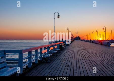 Alba al molo di legno chiamato Molo a Sopot, Polonia con luce solare riflesso sulle panchine Foto Stock