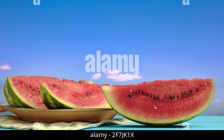 Fette di anguria concetto di frutta estiva. Cocomero fresco rosso dolce sano maturo in piastra su tavola di legno. Cibo succoso per la dieta, vegano, vegetariano. Blu Foto Stock