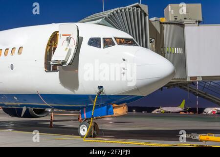 Aereo a getto passeggero con porta aperta all'aria ponte collegato a un'alimentazione esterna in un aeroporto grembiule notturno Foto Stock