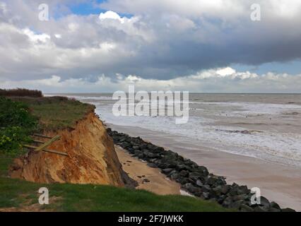 Una vista dalle scogliere erodenti sulla spiaggia con breakwater di roccia e mari moderati in una giornata ventosa a Happisburgh, Norfolk, Inghilterra, Regno Unito. Foto Stock