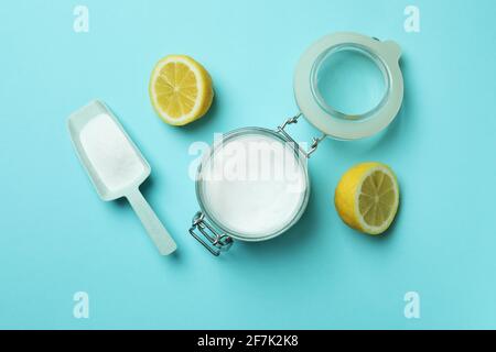 Sessola e vasetto con polvere acida e metà di limone su sfondo blu Foto Stock