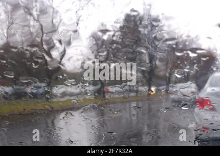 Gocce d'acqua sulla finestra in un giorno piovoso, strade bagnate Foto Stock