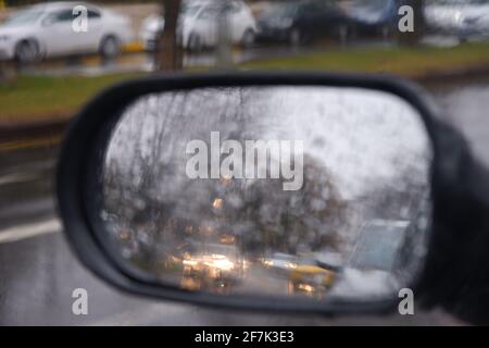 Vista dallo specchio retrovisore in una giornata piovosa con acqua gocce Foto Stock