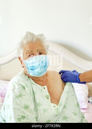 Anziano adulto anziano donna caucasica riceve il vaccino Covid-19 a casa dal medico Foto Stock