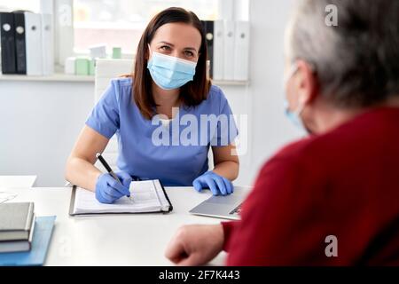 Sorridente dottoressa conduce un'intervista medica con il senior Foto Stock