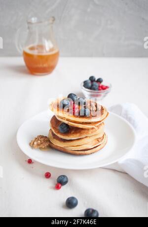 Deliziosi pancake appena cotti con miele, noce, miele, lamponi e mirtilli per colazione. Foto Stock