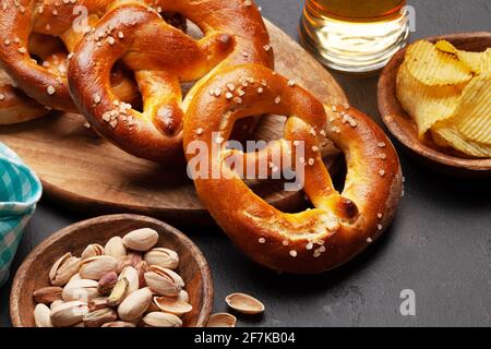 Tazza di birra lager, noci, patatine fritte e pretzel fatto in casa appena sfornato con sale marino. Classico spuntino con birra Foto Stock