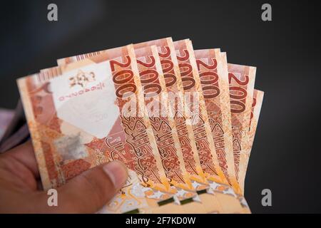 Mani degli uomini che tengono e contando le banconote della Banca Qatari. 200 nuove note di Rial. Concetto di business e finanza Foto Stock