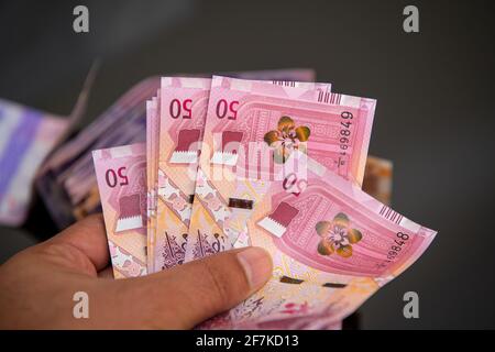 Mani degli uomini che tengono e contando le banconote della Banca Qatari. 50 nuove note di Rial. Concetto di business e finanza Foto Stock