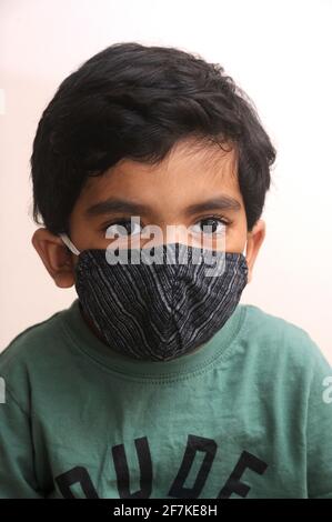 Ragazzo indiano che indossa maschera facciale come protezione personale contro l'inquinamento atmosferico o coronavirus COVID-19. Giovane hipster in maschera protettiva sul viso Foto Stock