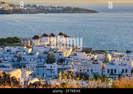 Splendida vista sui famosi mulini a vento bianchi al tramonto, Mykonos, Grecia. Case imbiancate di bianco, frizzante serata estiva, stile di vita mediterraneo Foto Stock