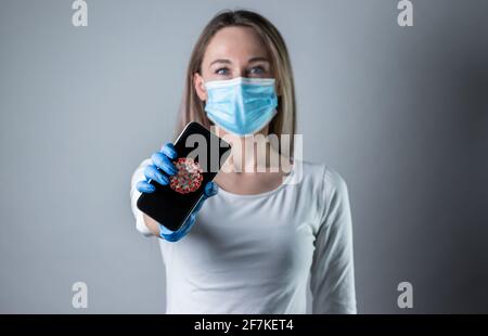 Donna che tiene smartphone con corona background.Confident giovane donna medico mostrare dispositivi medici, incoraggiare le persone a rimanere all'interno, combattere le malattie Foto Stock