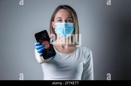 Donna che tiene smartphone con corona background.Confident giovane donna medico mostrare dispositivi medici, incoraggiare le persone a rimanere all'interno, combattere le malattie Foto Stock