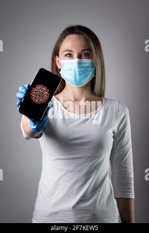 Donna che tiene smartphone con corona background.Confident giovane donna medico mostrare dispositivi medici, incoraggiare le persone a rimanere all'interno, combattere le malattie Foto Stock