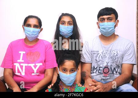 Famiglia indiana indossare maschera viso come protezione personale contro l'inquinamento atmosferico o coronavirus COVID-19. Giovane hipster in maschera protettiva sul viso Foto Stock