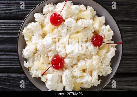 Insalata americana di dessert composta da riso, marshmallows e ananas condita con panna montata da vicino in un piatto sul tavolo. Vista dall'alto orizzontale Foto Stock