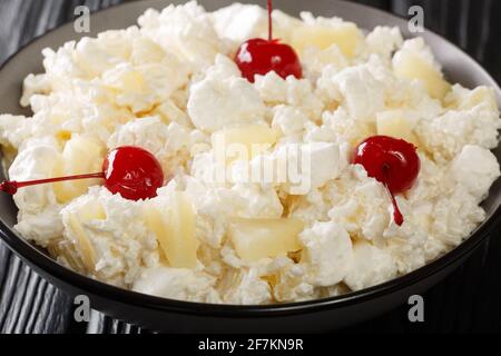 Insalata americana di dessert composta da riso, marshmallows e ananas condita con panna montata da vicino in un piatto sul tavolo. Orizzontale Foto Stock