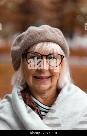 Signora caucasica felice in beret elegante, coperta accogliente su una passeggiata in una giornata ventosa in autunno o in autunno Foto Stock