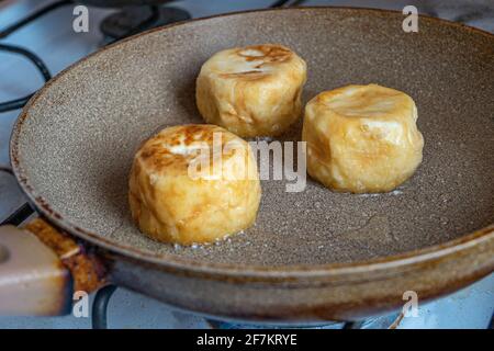 Frittelle di formaggio, cheesecake, frittelle di ricotta fritte in una padella in olio caldo. Foto Stock