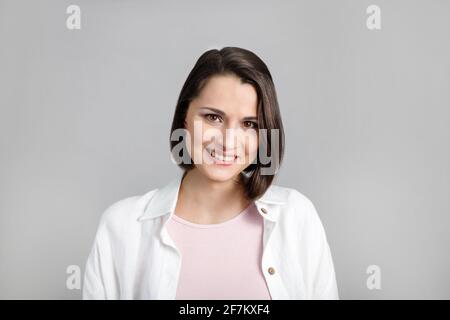 Ritratto di giovane donna multietnica bruna sorridente in canotta rosa e camicia bianca. Foto Stock