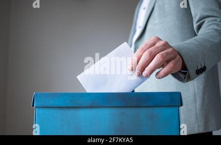 mano maschile che mette il voto in scrutinio Foto Stock