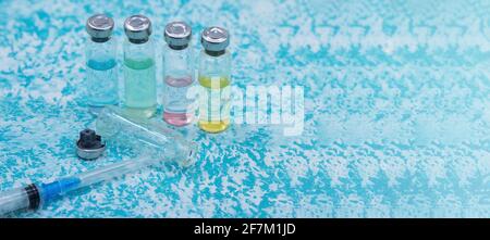Prevenzione delle malattie stagionali. Fiale mediche, siringhe e una maschera su sfondo verde. Vaccinazione contro covid-19. Foto Stock