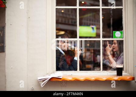 30s giovani professionisti, uomo e donna locali che parlano nel pub, bere birra alla finestra. Vivere tutti i giorni a Londra, Regno Unito. Ago 2015 Foto Stock