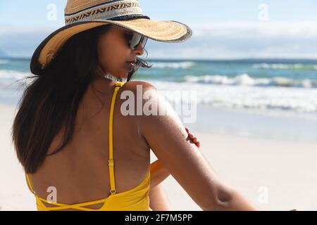 Donna mista in vacanza al mare con crema solare Foto Stock