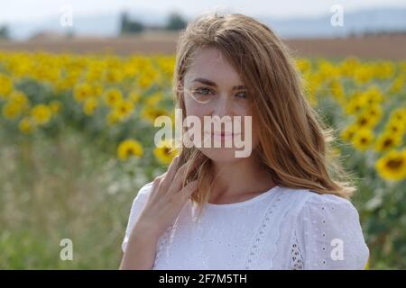 Donna in posa a macchina fotografica in un campo di girasoli, Valensole, Provenza, Francia Foto Stock