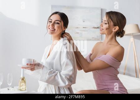 bella donna che fa acconciatura a sposa felice in abito di seta Foto Stock